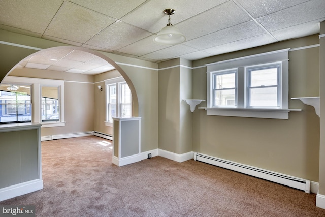 carpeted spare room with arched walkways, baseboard heating, and a paneled ceiling