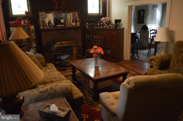 living area with a brick fireplace and wood finished floors