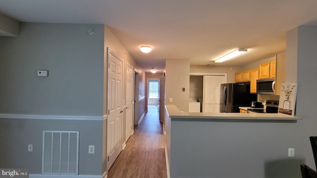 kitchen featuring washer / clothes dryer, appliances with stainless steel finishes, dark wood-type flooring, and kitchen peninsula