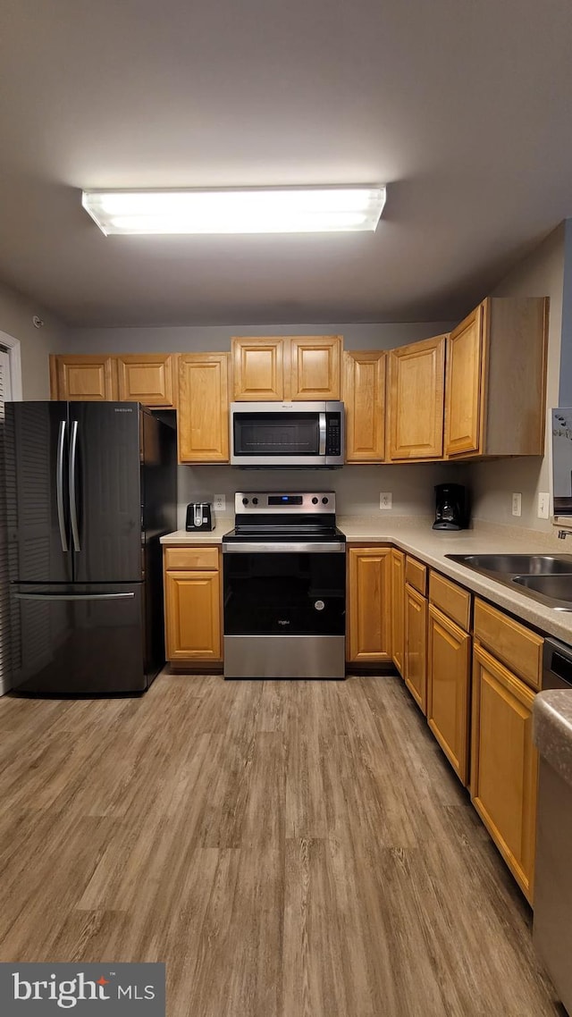 kitchen featuring stainless steel appliances, sink, and light hardwood / wood-style flooring