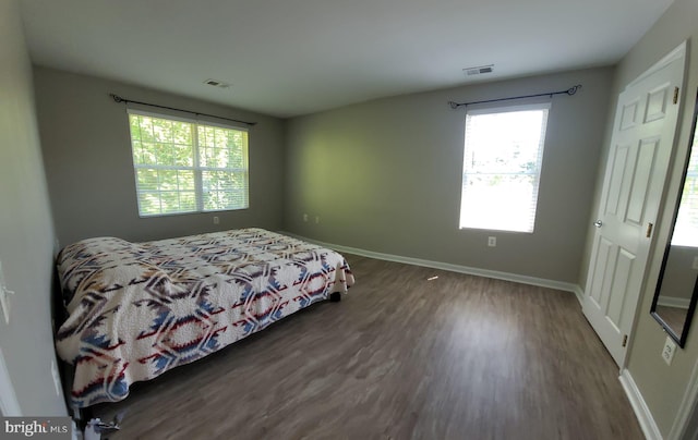 bedroom featuring dark wood-type flooring and multiple windows