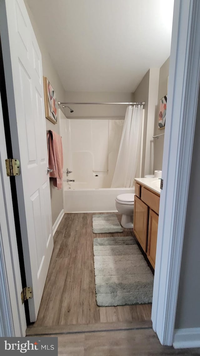 full bathroom with hardwood / wood-style floors, toilet, shower / tub combo, and vanity