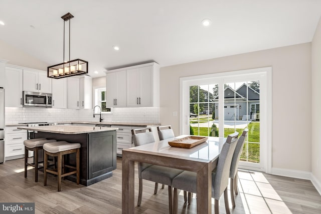 kitchen featuring a kitchen island, decorative light fixtures, light hardwood / wood-style flooring, tasteful backsplash, and white cabinets