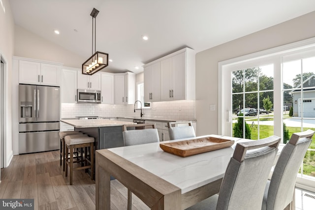 kitchen featuring a kitchen island, a kitchen breakfast bar, pendant lighting, stainless steel appliances, and lofted ceiling