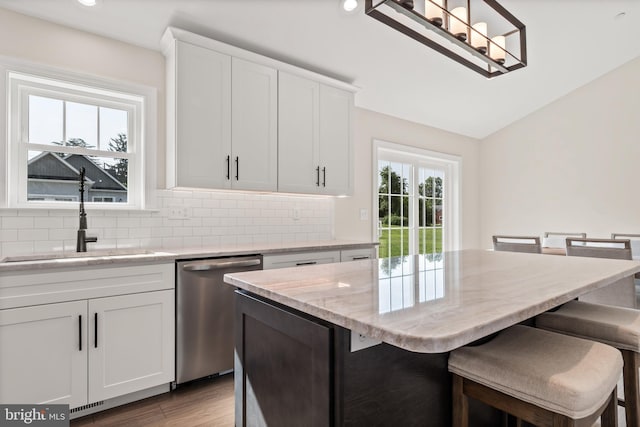 kitchen featuring light hardwood / wood-style flooring, dishwasher, sink, a center island, and white cabinets