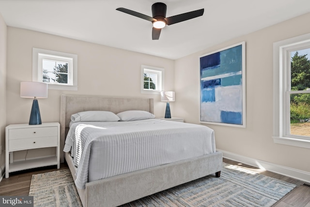 bedroom with multiple windows, wood-type flooring, and ceiling fan