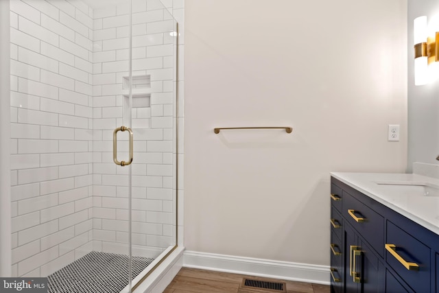 full bathroom with wood finished floors, vanity, visible vents, baseboards, and a stall shower