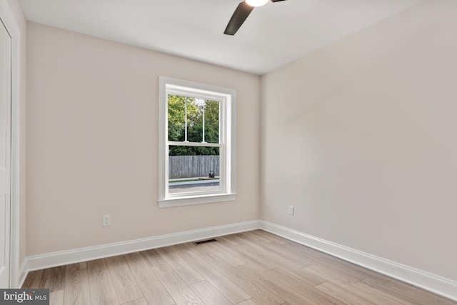 empty room featuring light wood finished floors, a ceiling fan, and baseboards