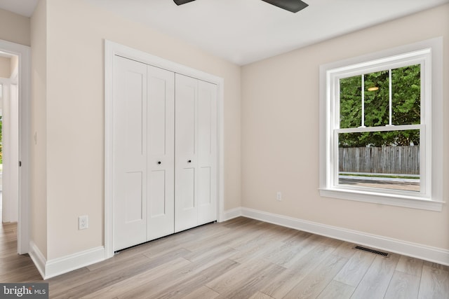 unfurnished bedroom featuring multiple windows, ceiling fan, a closet, and light hardwood / wood-style flooring