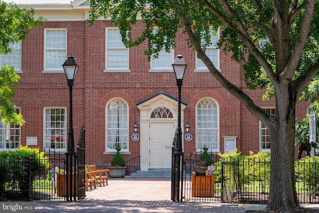 view of front of home with entry steps, brick siding, and fence