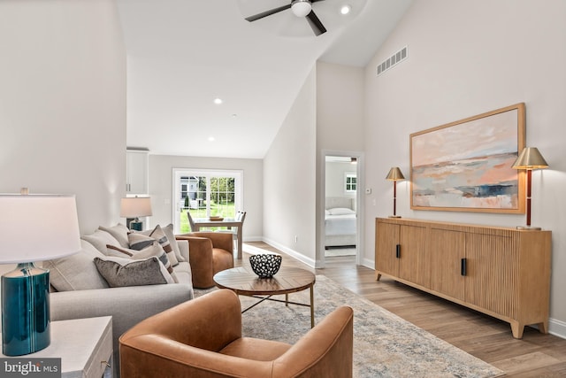 living room with light wood-type flooring, ceiling fan, and high vaulted ceiling