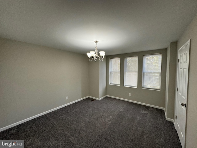 carpeted spare room with a chandelier