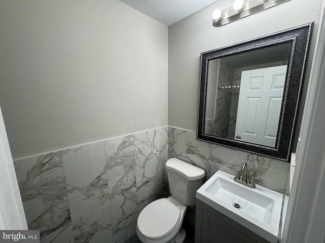 bathroom featuring tile walls, vanity, and toilet