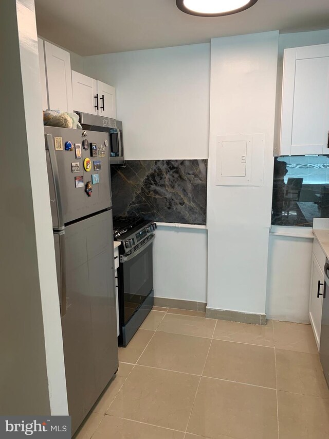 kitchen with stainless steel fridge, white cabinets, white gas range, and backsplash