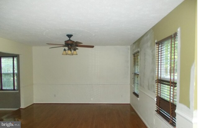 spare room featuring ceiling fan, a wealth of natural light, and dark hardwood / wood-style flooring