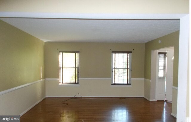 unfurnished room with a wealth of natural light and dark hardwood / wood-style flooring