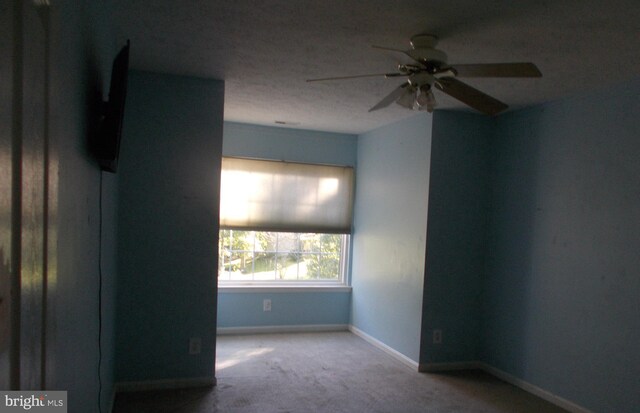 empty room with a textured ceiling, ceiling fan, and carpet