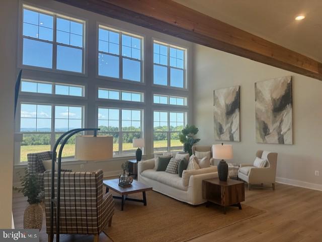 interior space featuring recessed lighting, wood finished floors, a towering ceiling, baseboards, and beamed ceiling