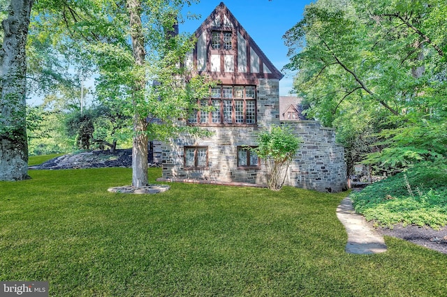 rear view of house with stone siding and a yard