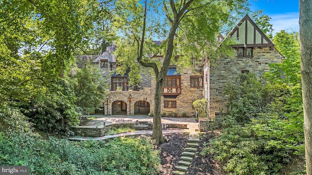 view of front facade featuring stone siding and a patio