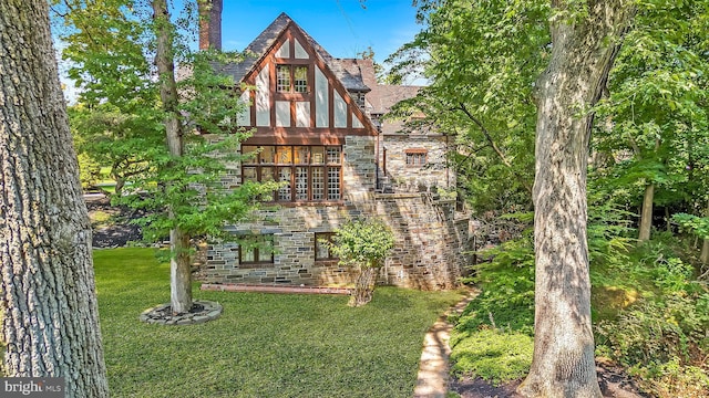 view of front of property with a front yard, stone siding, and a chimney