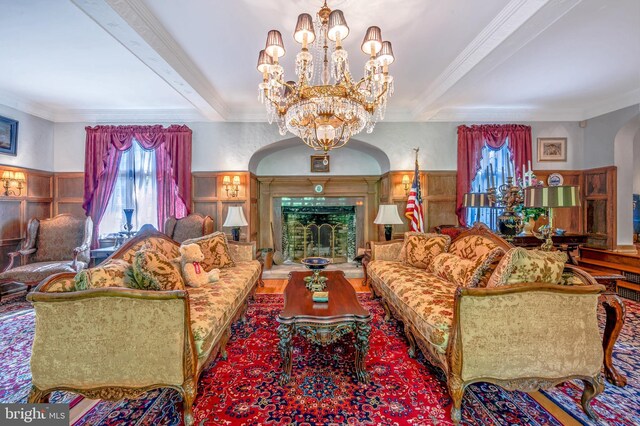 living area featuring a wainscoted wall, beam ceiling, and crown molding