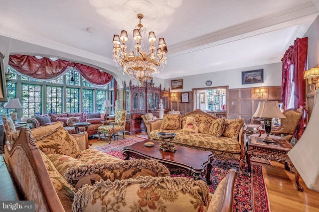 living room with ornamental molding, a chandelier, and wood finished floors