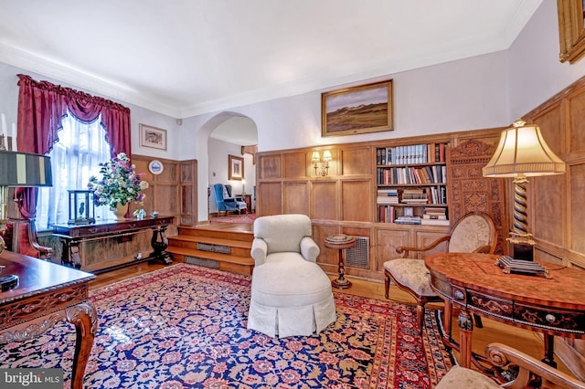 interior space with arched walkways, wood finished floors, and ornamental molding