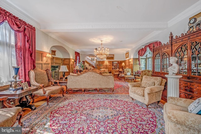 living room with ornamental molding, a notable chandelier, and wainscoting