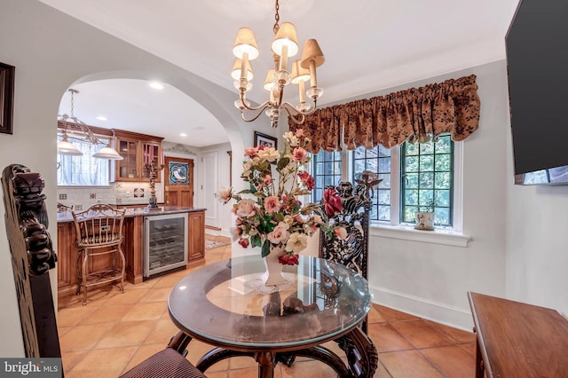 dining area featuring beverage cooler, baseboards, arched walkways, a notable chandelier, and indoor wet bar