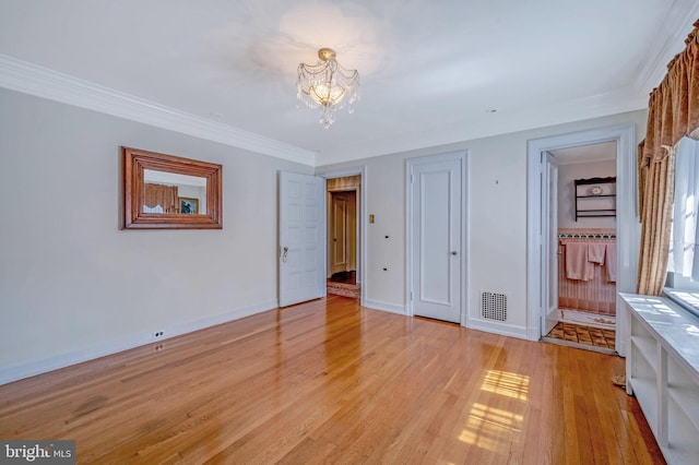 unfurnished bedroom with a notable chandelier, visible vents, baseboards, light wood-style floors, and ornamental molding