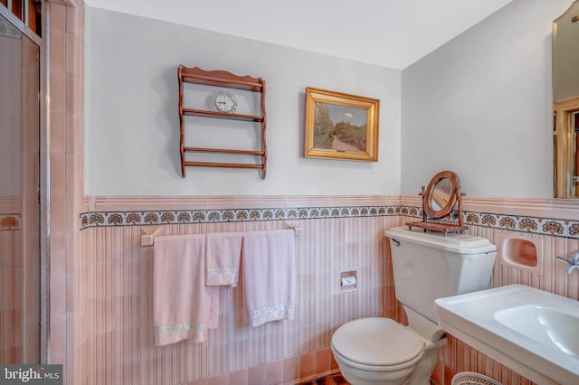 full bathroom with toilet, a wainscoted wall, tile walls, and tiled shower