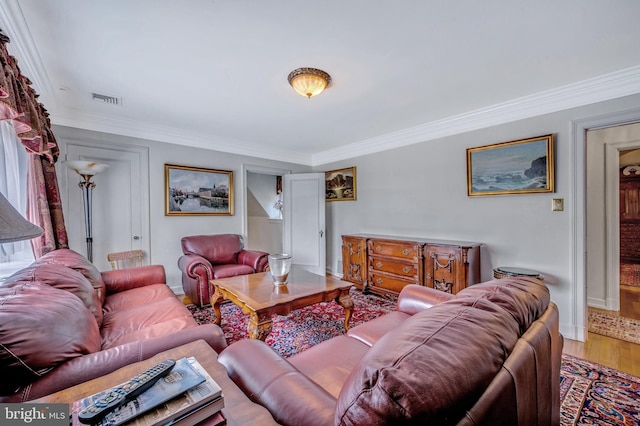 living room featuring ornamental molding, visible vents, baseboards, and wood finished floors