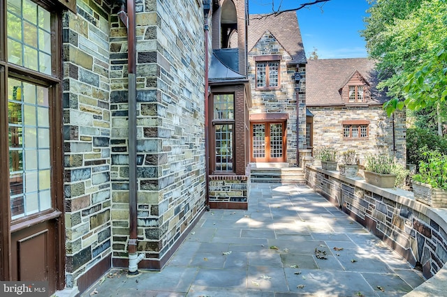 entrance to property featuring stone siding, french doors, and brick siding