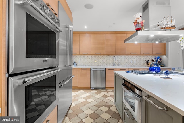 kitchen featuring appliances with stainless steel finishes, light brown cabinets, island range hood, and tasteful backsplash