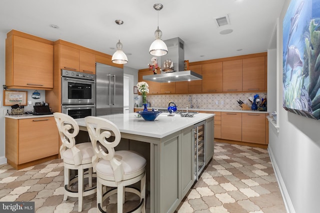 kitchen with decorative light fixtures, a kitchen island with sink, island exhaust hood, a breakfast bar, and stainless steel appliances