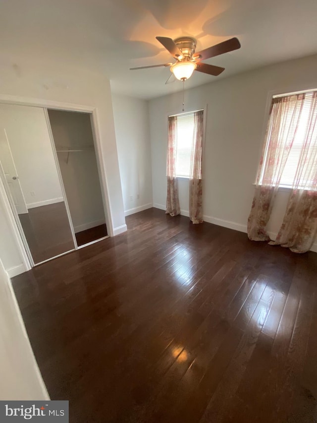 unfurnished bedroom featuring dark wood-type flooring, ceiling fan, and a closet