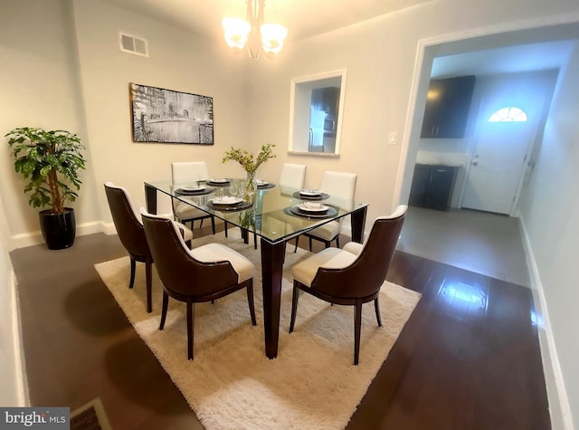 dining room with a chandelier, visible vents, baseboards, and wood finished floors