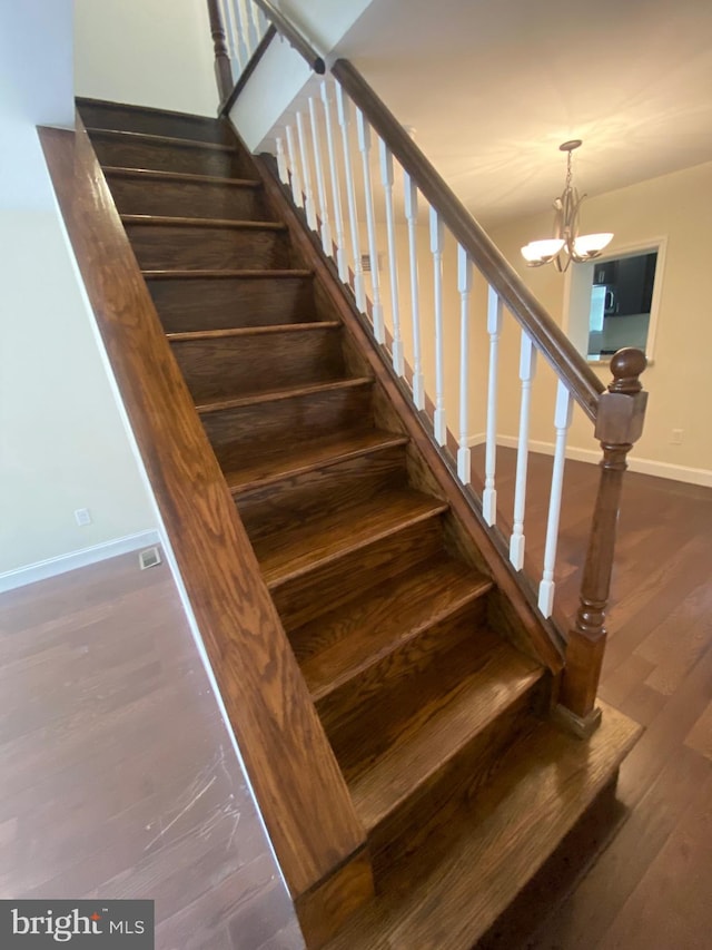 staircase featuring hardwood / wood-style flooring and a notable chandelier