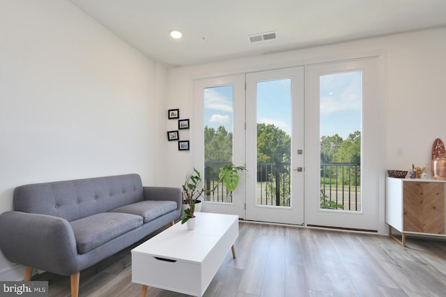 living room featuring plenty of natural light, light wood-type flooring, and french doors