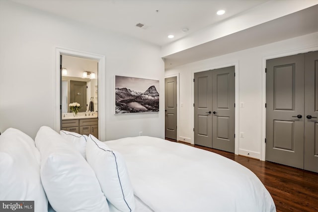 bedroom with dark wood-type flooring and connected bathroom