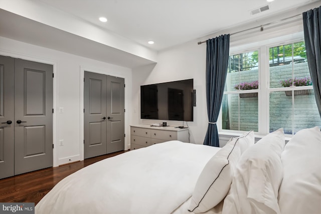 bedroom featuring dark hardwood / wood-style floors and multiple closets