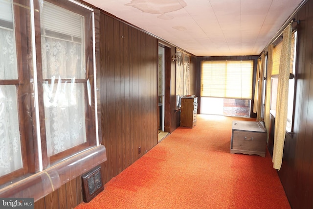 corridor with carpet floors, visible vents, and wooden walls