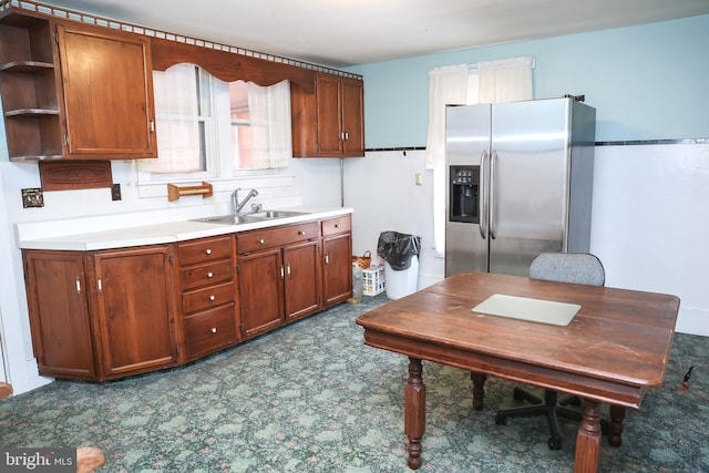 kitchen with open shelves, brown cabinetry, stainless steel refrigerator with ice dispenser, and a sink