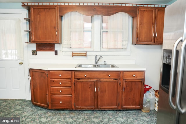 kitchen featuring brown cabinets, stainless steel fridge, a sink, and open shelves