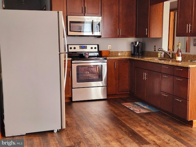 kitchen with light stone counters, stainless steel appliances, dark hardwood / wood-style floors, and sink