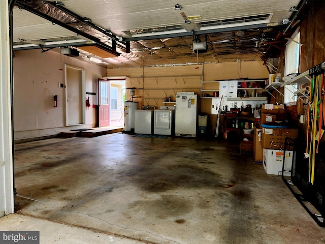 garage featuring white refrigerator, electric water heater, a garage door opener, and washer and dryer