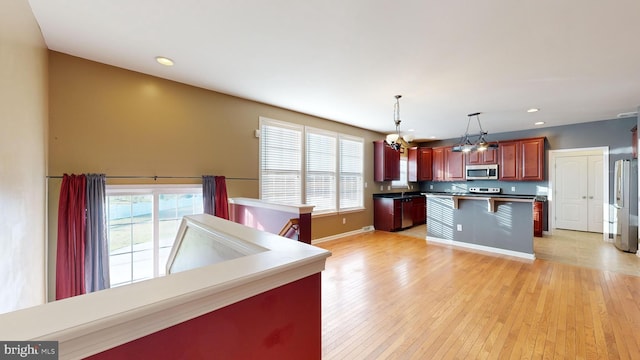 kitchen featuring light wood-style floors, appliances with stainless steel finishes, a kitchen breakfast bar, and a wealth of natural light