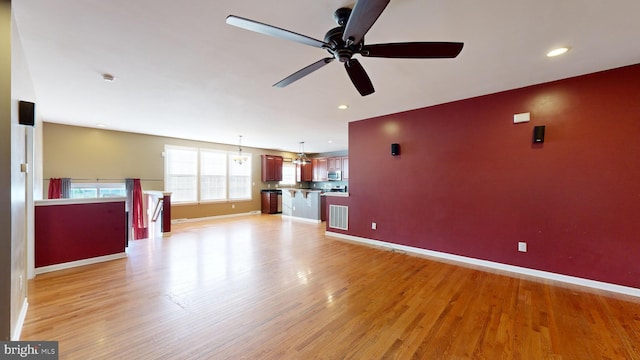 unfurnished living room featuring light wood-style floors, visible vents, and baseboards