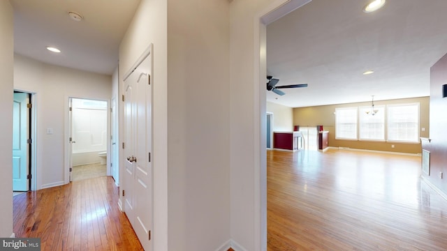 hall featuring baseboards, wood finished floors, and recessed lighting